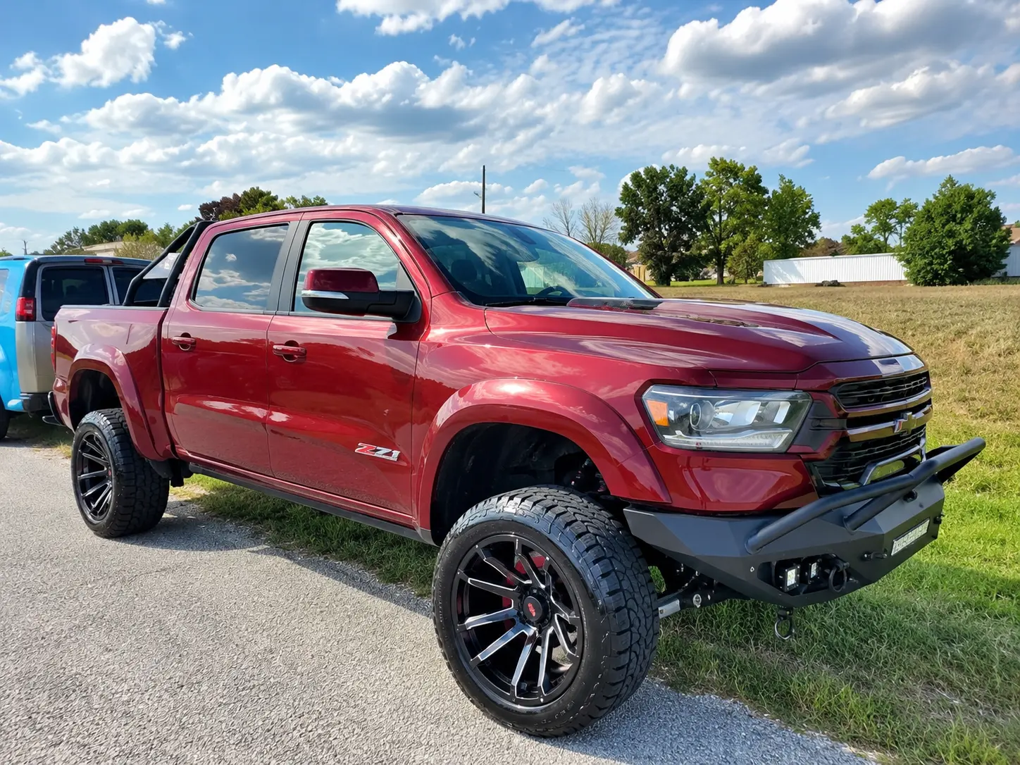 Red Chevrolet Colorado pickup truck with custom wheels parked on rural road
