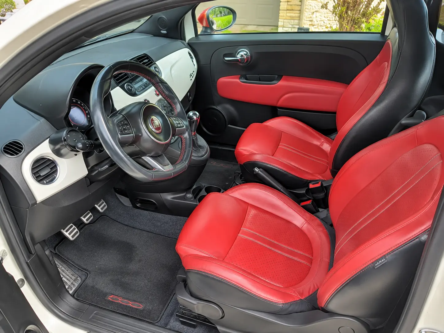 Interior of white Fiat 500 with red and black leather seats and steering wheel